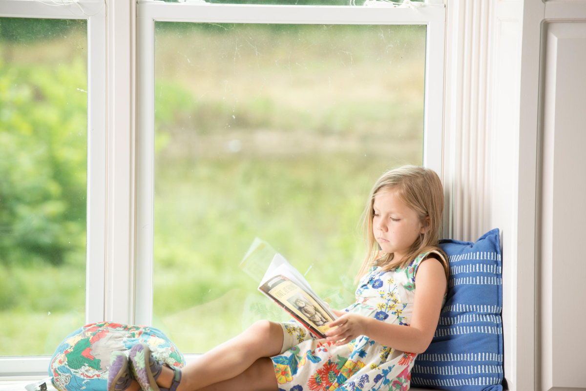 Girl reading a book on a window seat